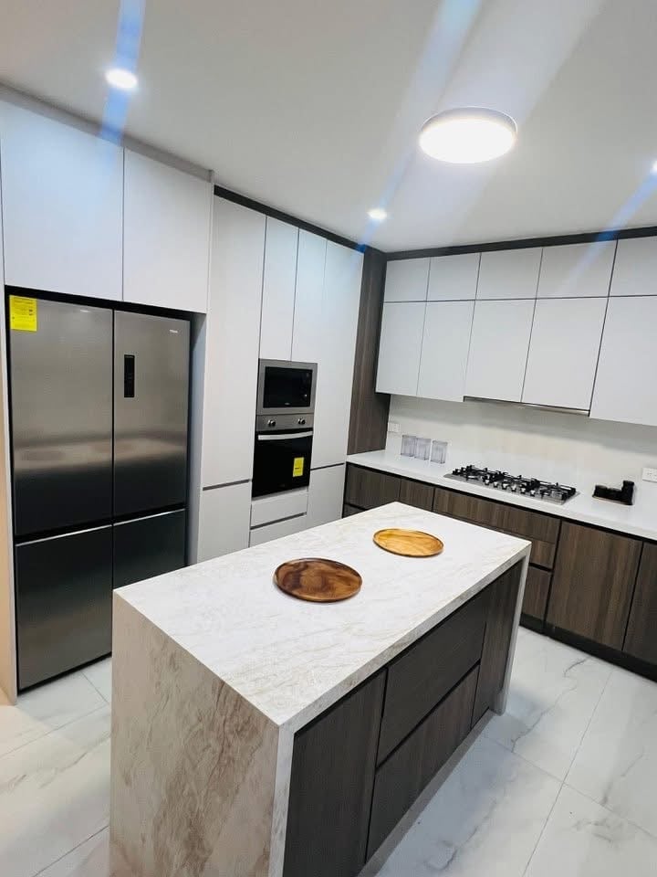 Modern kitchen with white and dark wood cabinetry, marble island countertop, stainless steel appliances, and recessed ceiling lights