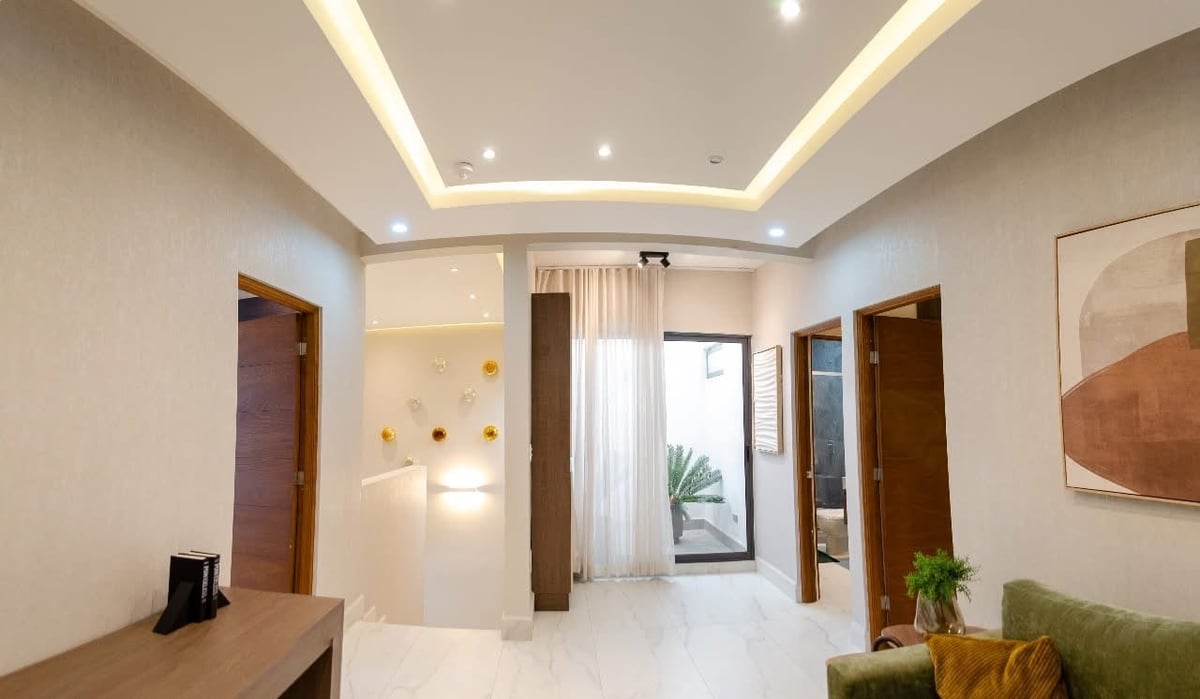 Modern apartment entrance hallway with white walls, coffered ceiling with recessed lighting, wooden doors, and minimalist decor