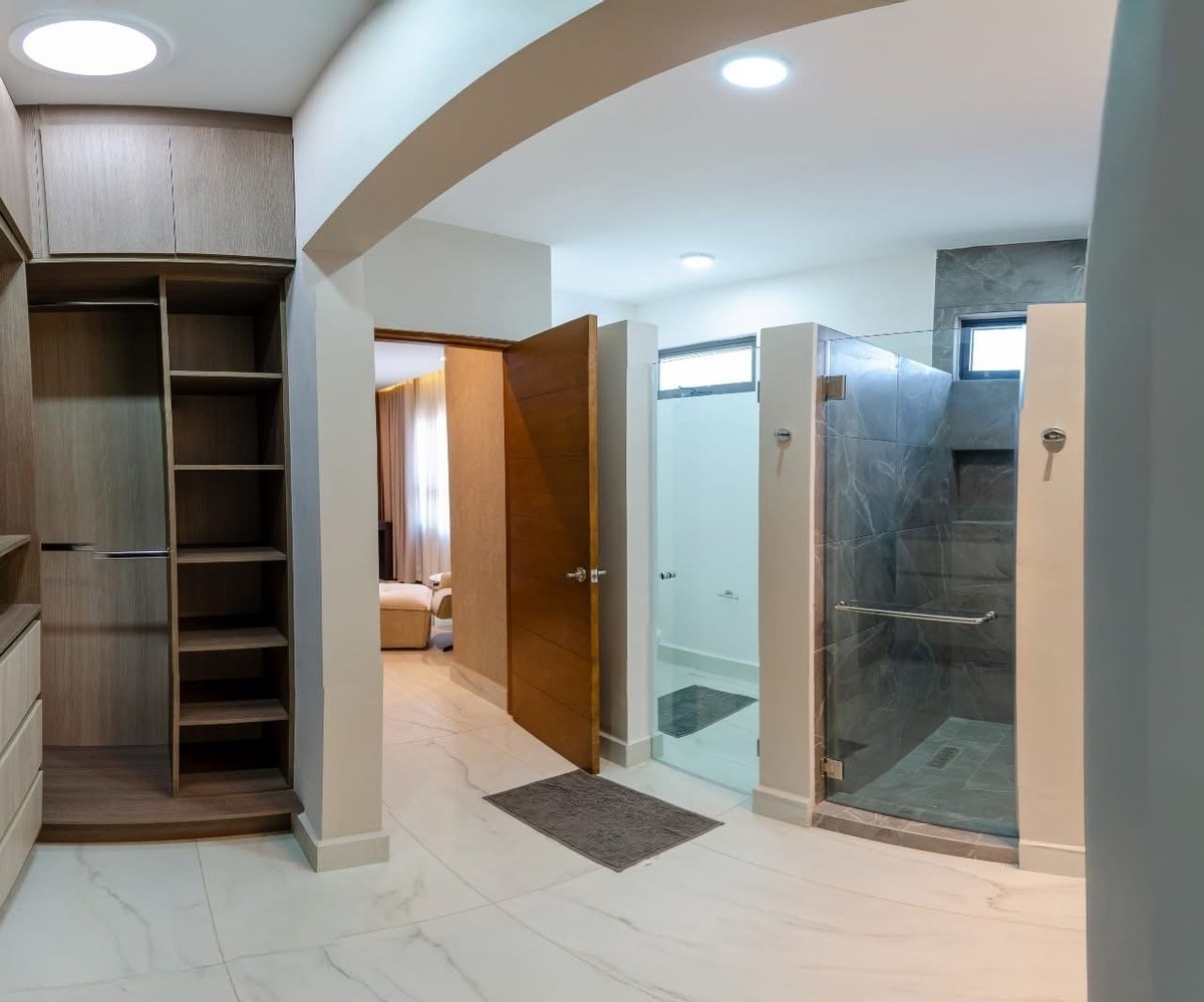 Modern master bathroom with marble flooring, curved ceiling, walk-in closet, and dual glass shower enclosures